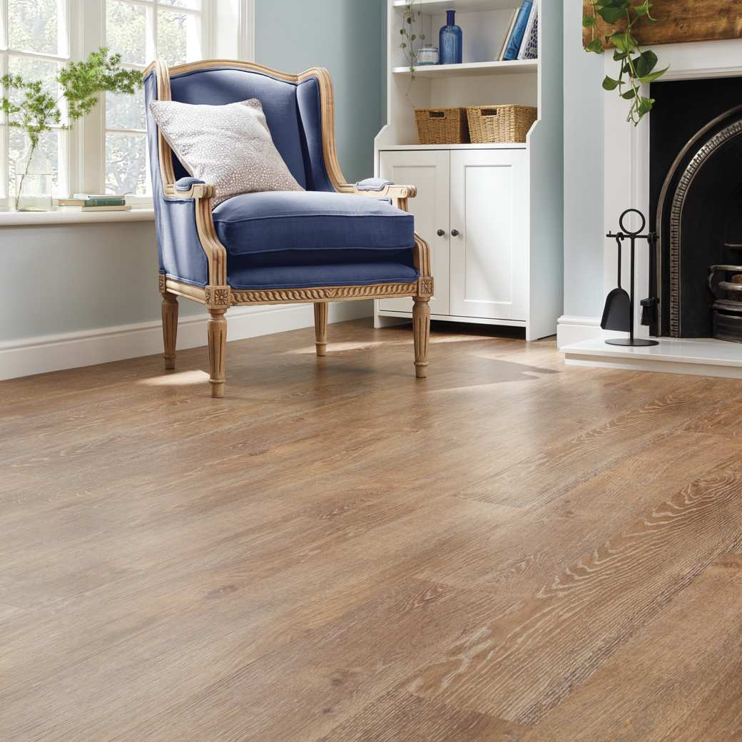 Chair beside a living room fireplace with Honey Oak lvp floors; Van Gogh is avaiable in gluedown and rigid core